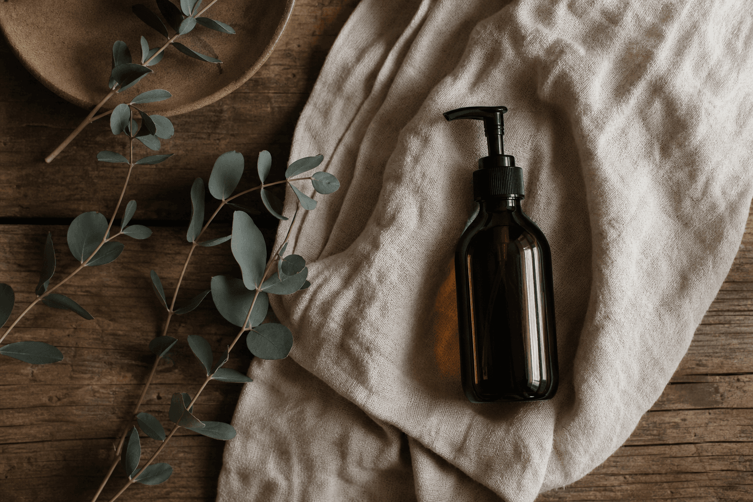 Rustic table with massage oil and eucalyptus leaves
